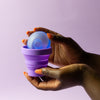 Bohokiwi Ocean Blue menstrual disc being placed into a Purple collapsible menstrual cup and disc steriliser